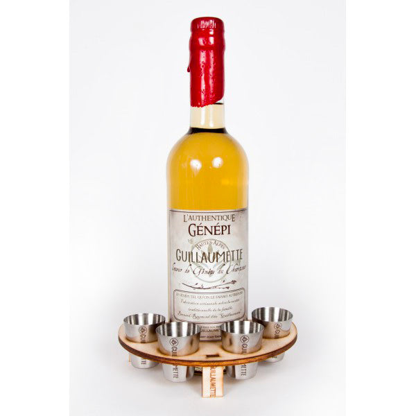 Set de verres en inox Guillaumette disposés dans un support circulaire en bois, posé autour d’une bouteille de génépi artisanal Guillaumette. Le support et les verres sont gravés avec soin pour refléter l’authenticité et la tradition du produit.